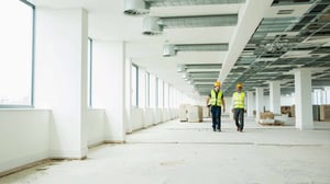 Two architects walk through a vacant office undergoing renovations