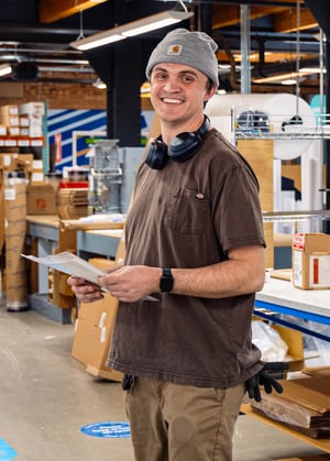 Jake Stanley in the Print Shop holding documents and smiling