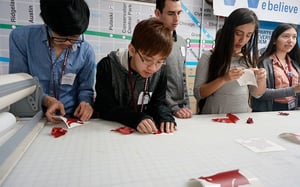 A group of young men are sitting at a table working on a project .