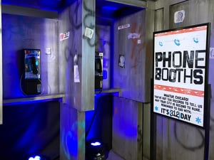 Two pay phones are sitting next to each other in a room with blue lights .