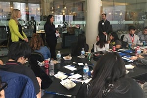 A woman is giving a presentation to a group of people sitting around a table .