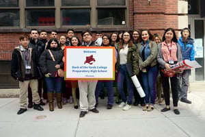 A group of people standing in front of a sign that says back of the yards college preparatory high school