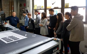 A group of people are standing around a machine in a room .