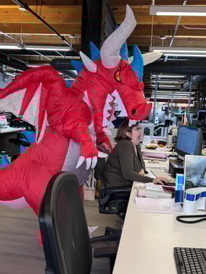 Amanda Eich pretending to be eaten by someone in an inflatable dragon suit