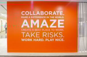 Bright orange wall lists inspirational phrases in an office setting.