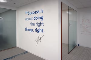 Inspirational quote in vinyl letters on an office wall.
