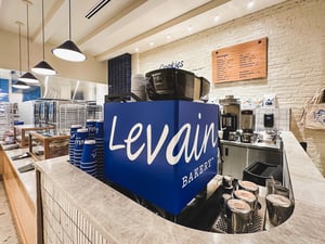 A custom branded coffee machine with Levain’s logo at the front counter, showcasing point of purchase signage, a menu, and branded wall graphics in the background.