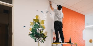 The installer stretches and adheres the printed vinyl to the wall, ensuring proper placement and a smooth application for the large-format graphic.