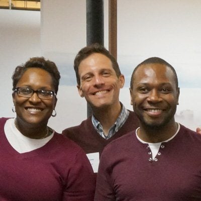 Three people are posing for a picture together and smiling for the camera
